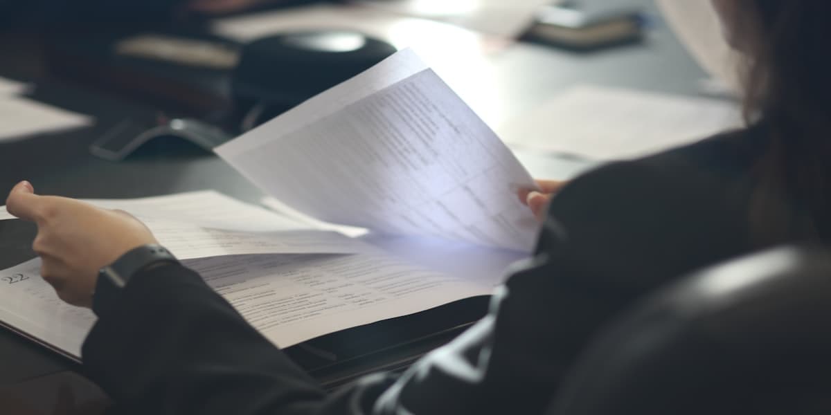 Persona che legge documenti stampati a una scrivania